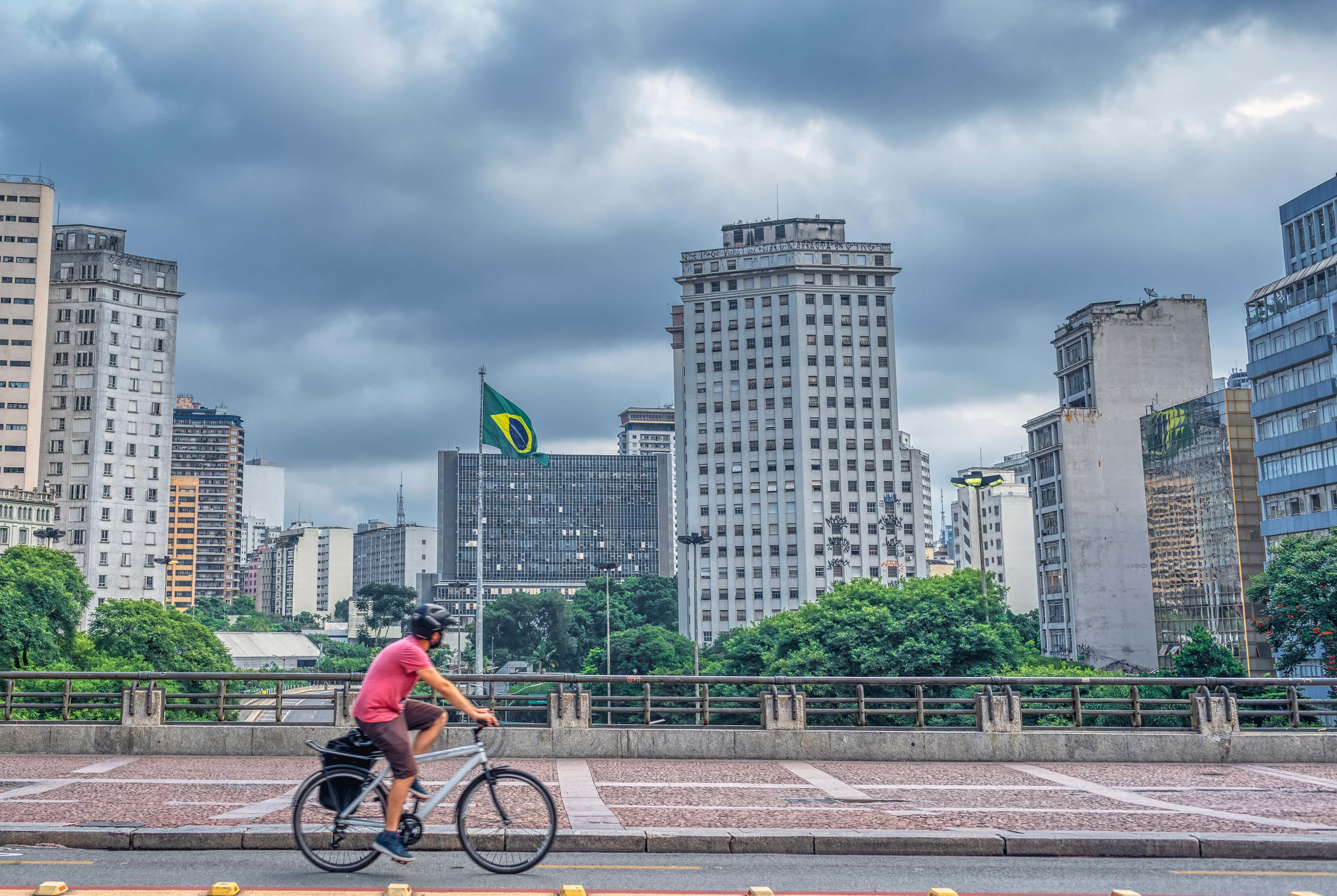 A man riding his bike in Sao Paolo with the city skyline visible behind him