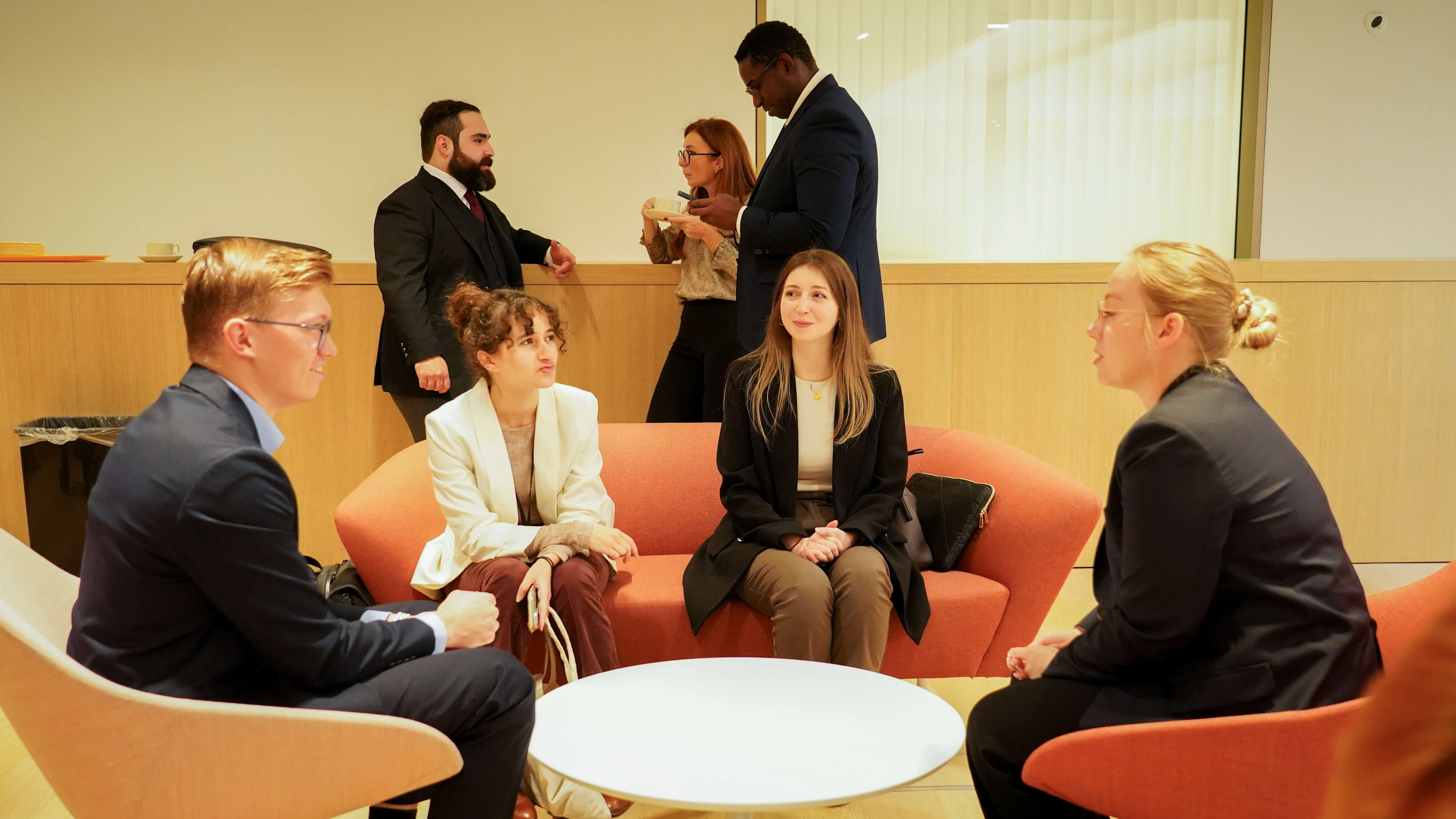 3 women and 1 man in business wear having a conversation at a conference