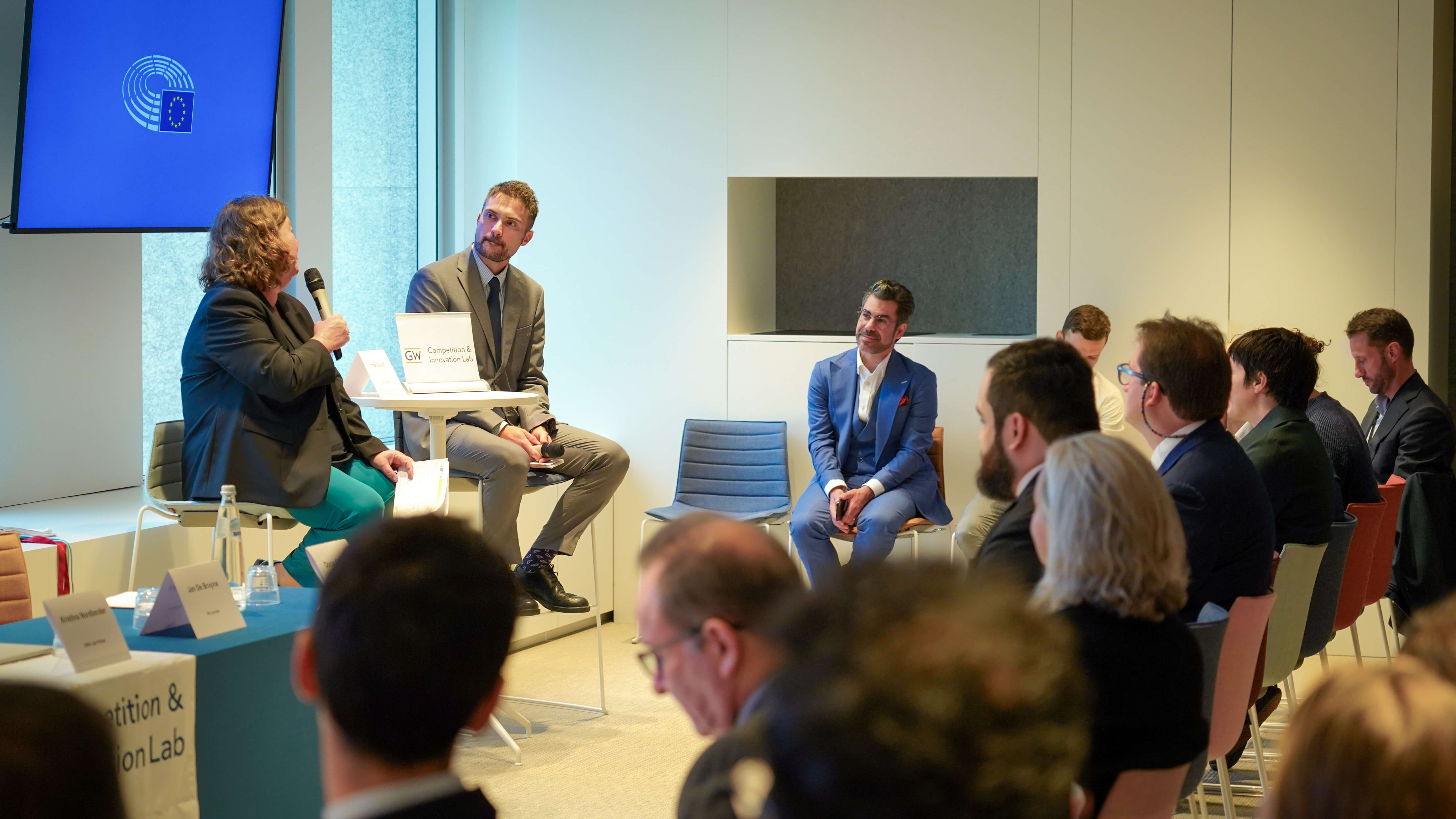 a crowd of people in business wear watches a man and a woman present at a conference