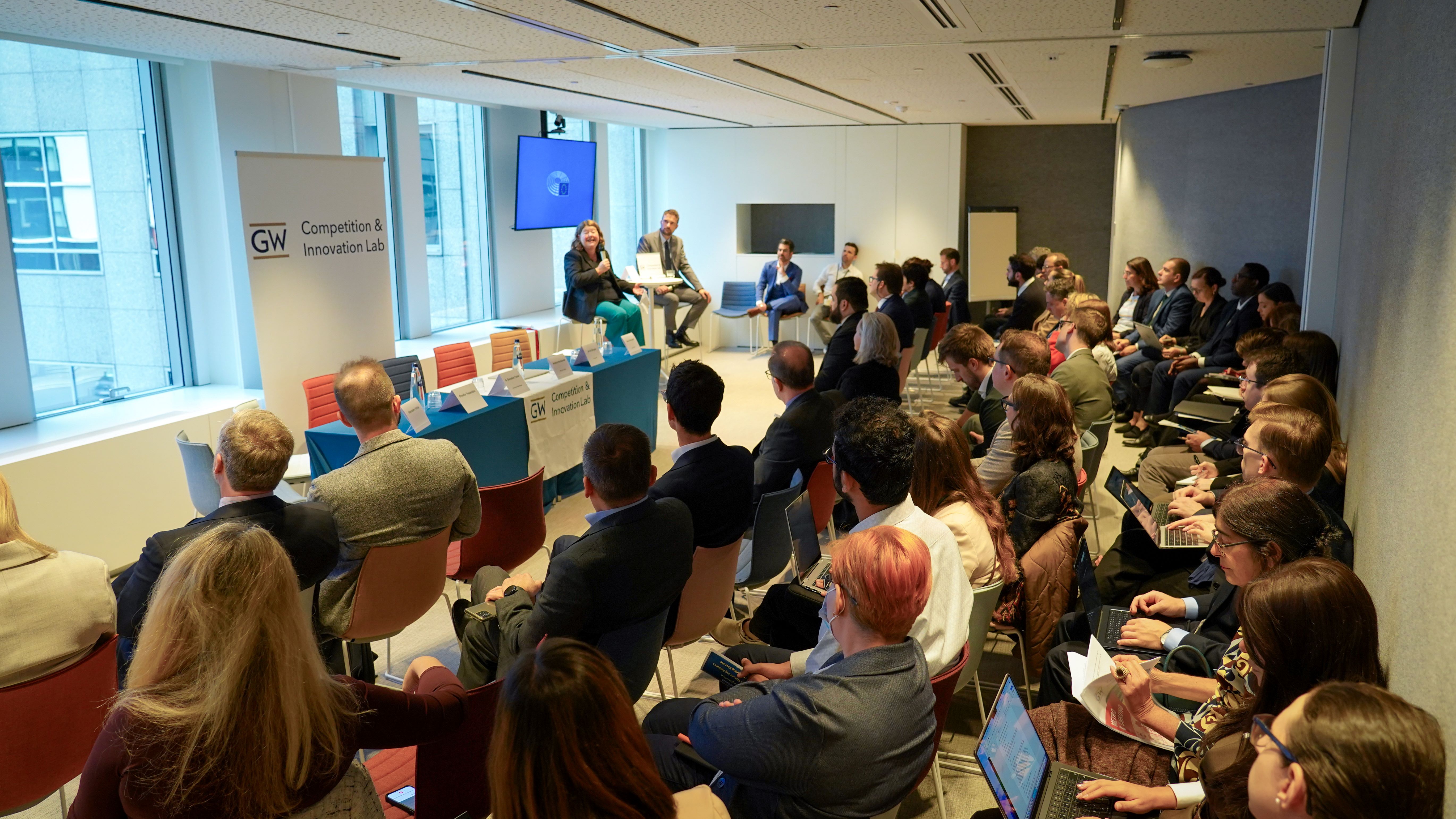 a crowd of people in business wear watches a conference presentation