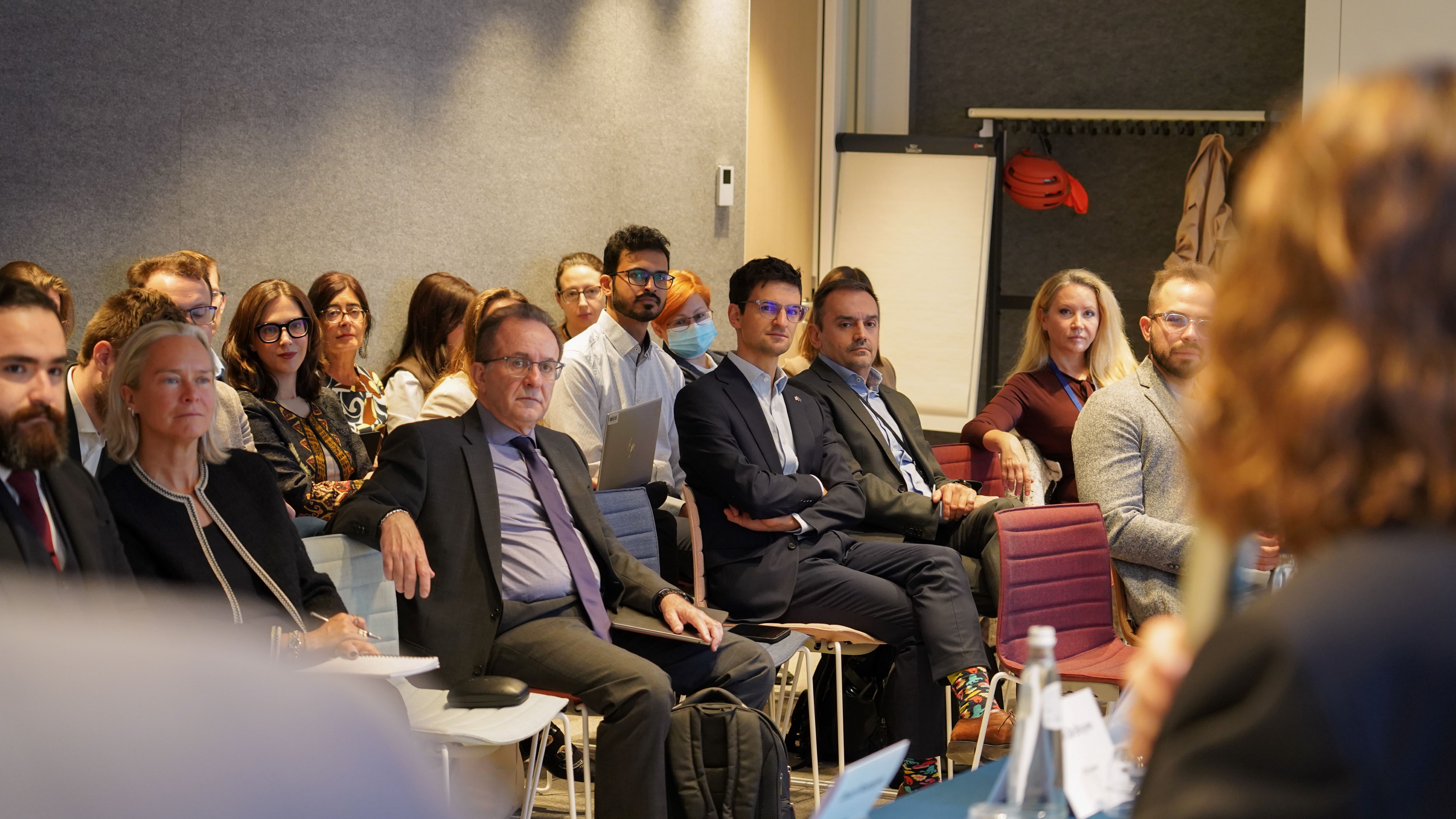 a crowd of people in business wear watches a conference presentation