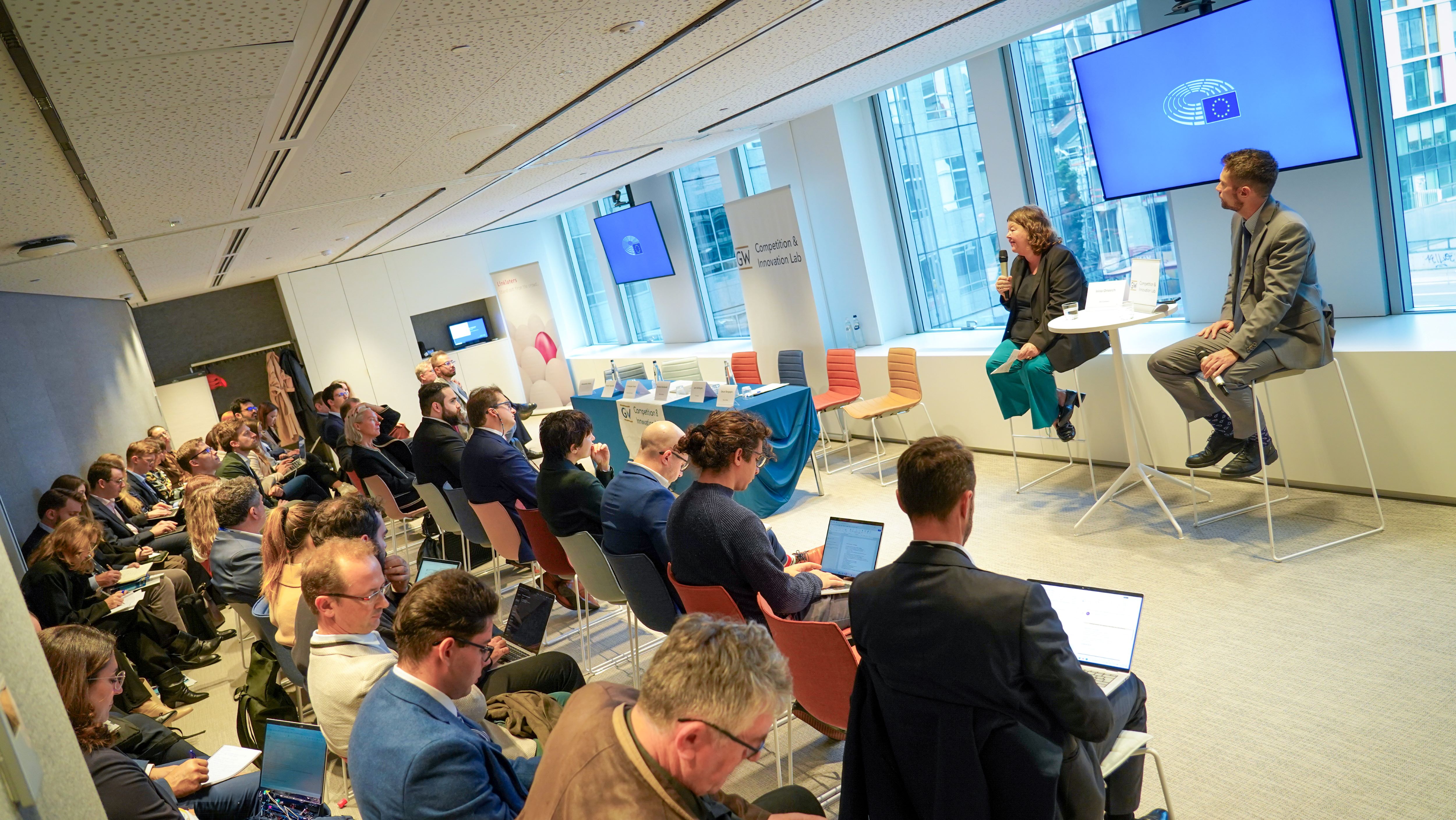 a crowd of people in business wear watches a conference presentation