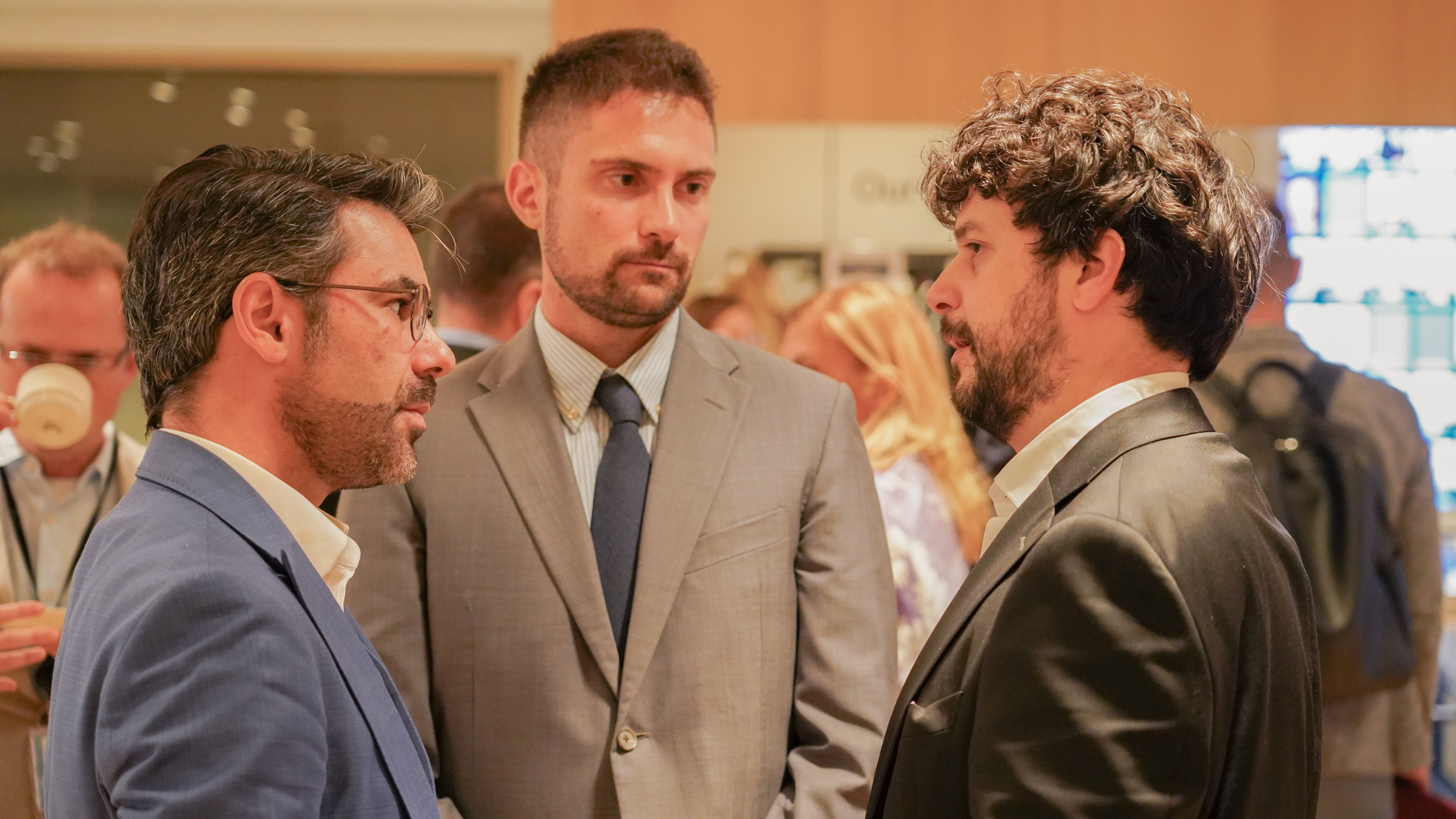 3 men in suits having a conversation at a conference