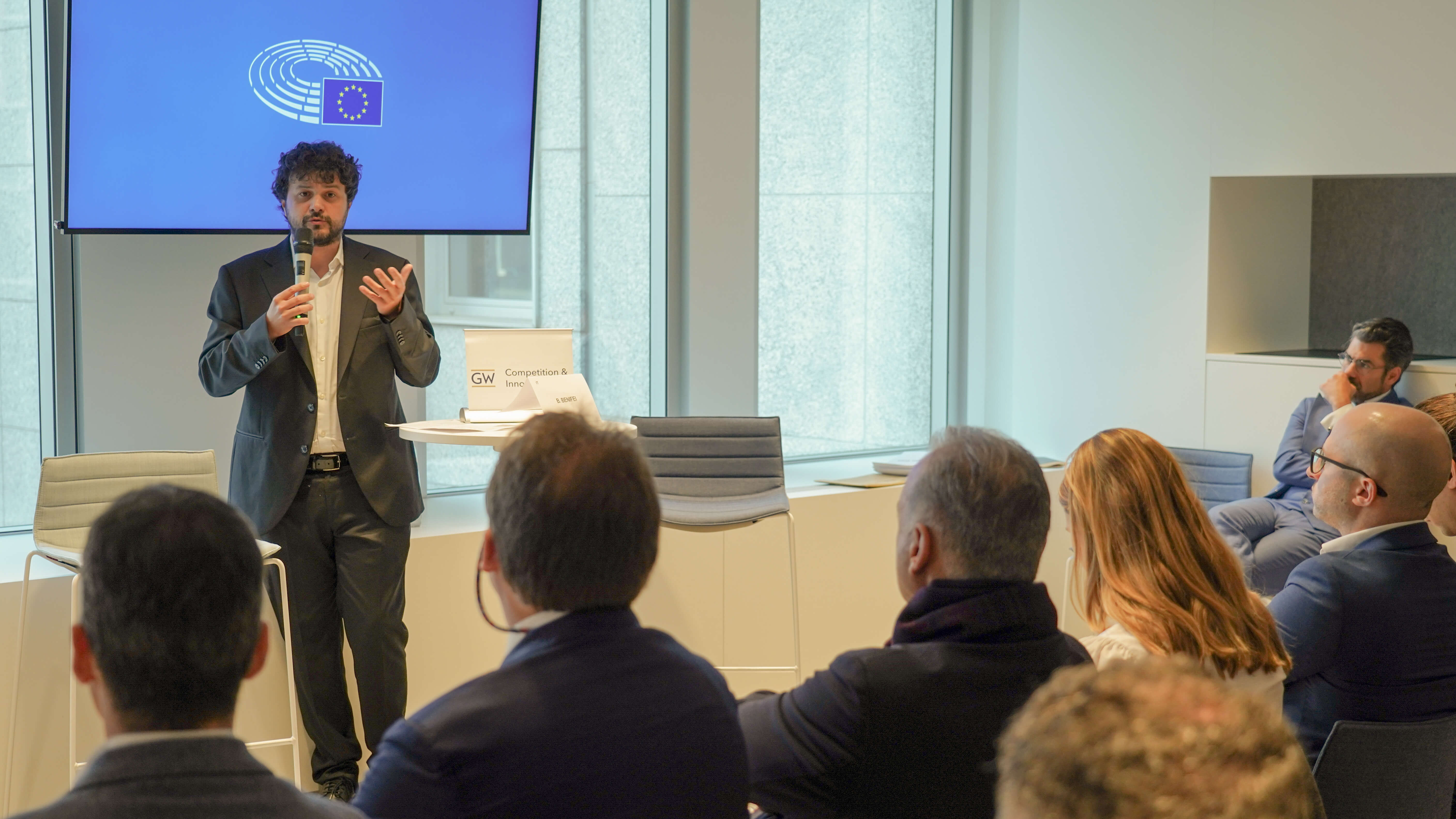 a man in a suit gives a conference presentation to a crowd in business wear