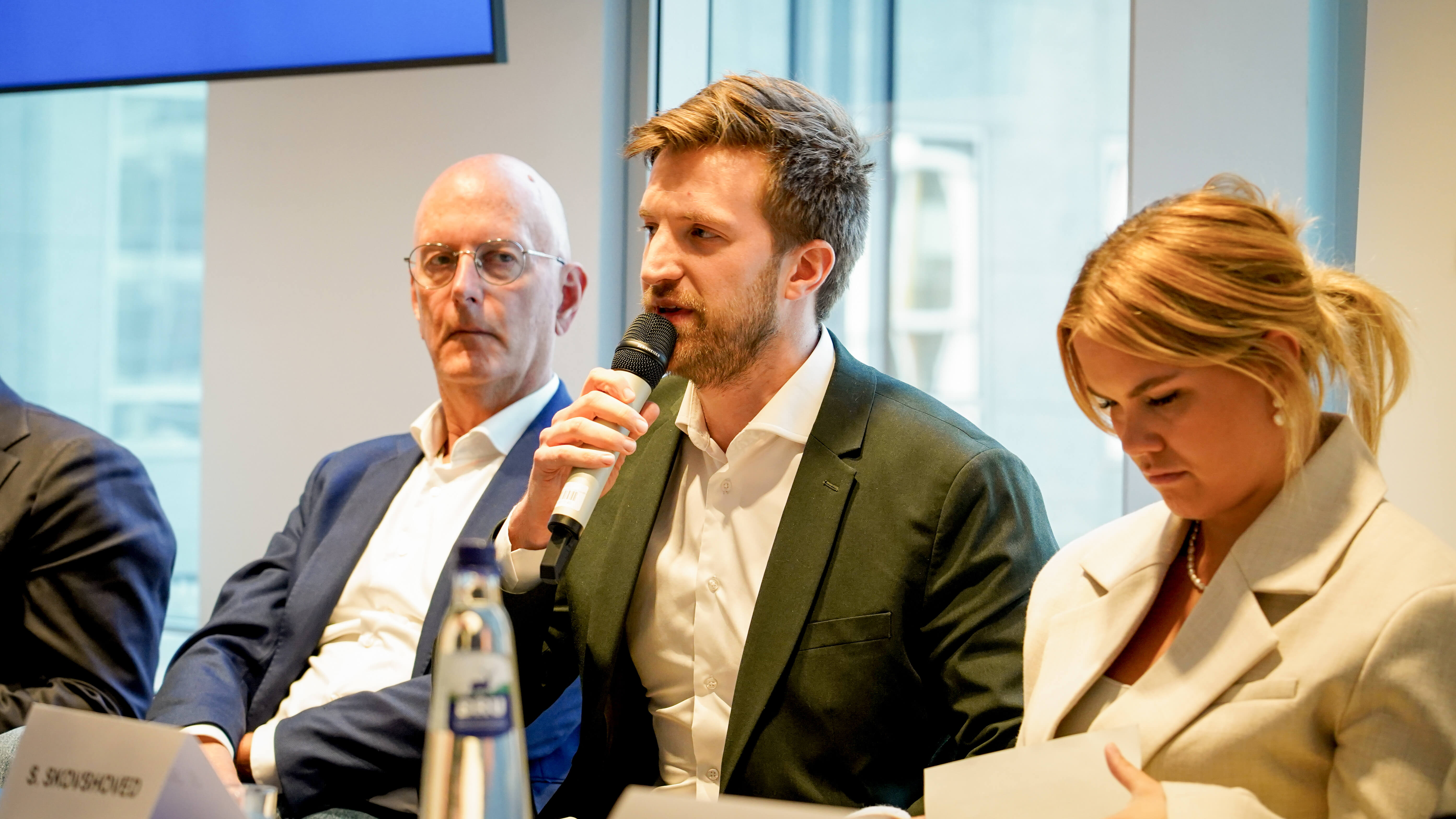 2 men and 1 woman in business wear give a conference presentation on a panel