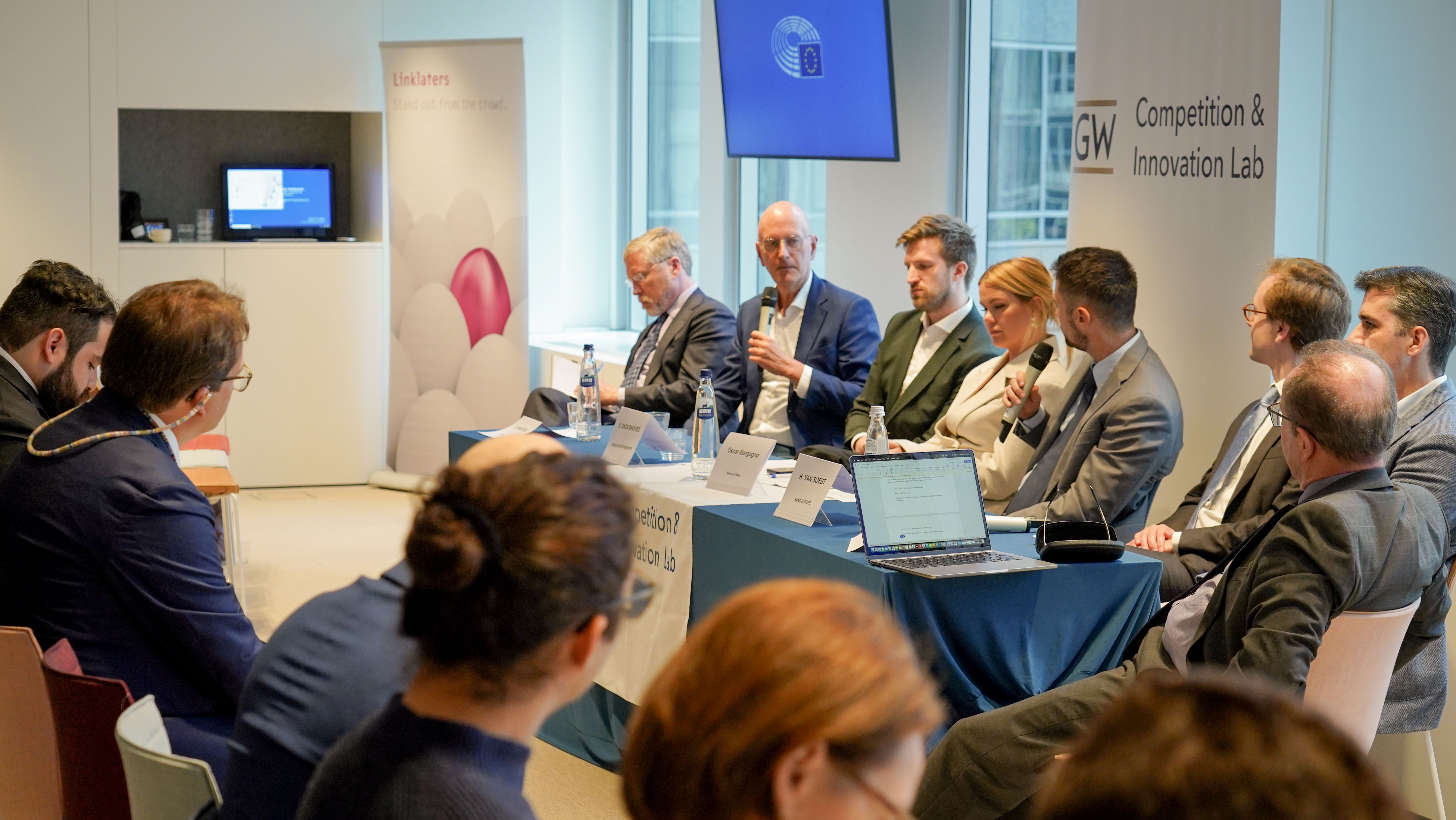 a crowd of people in business wear watches a panel during a conference