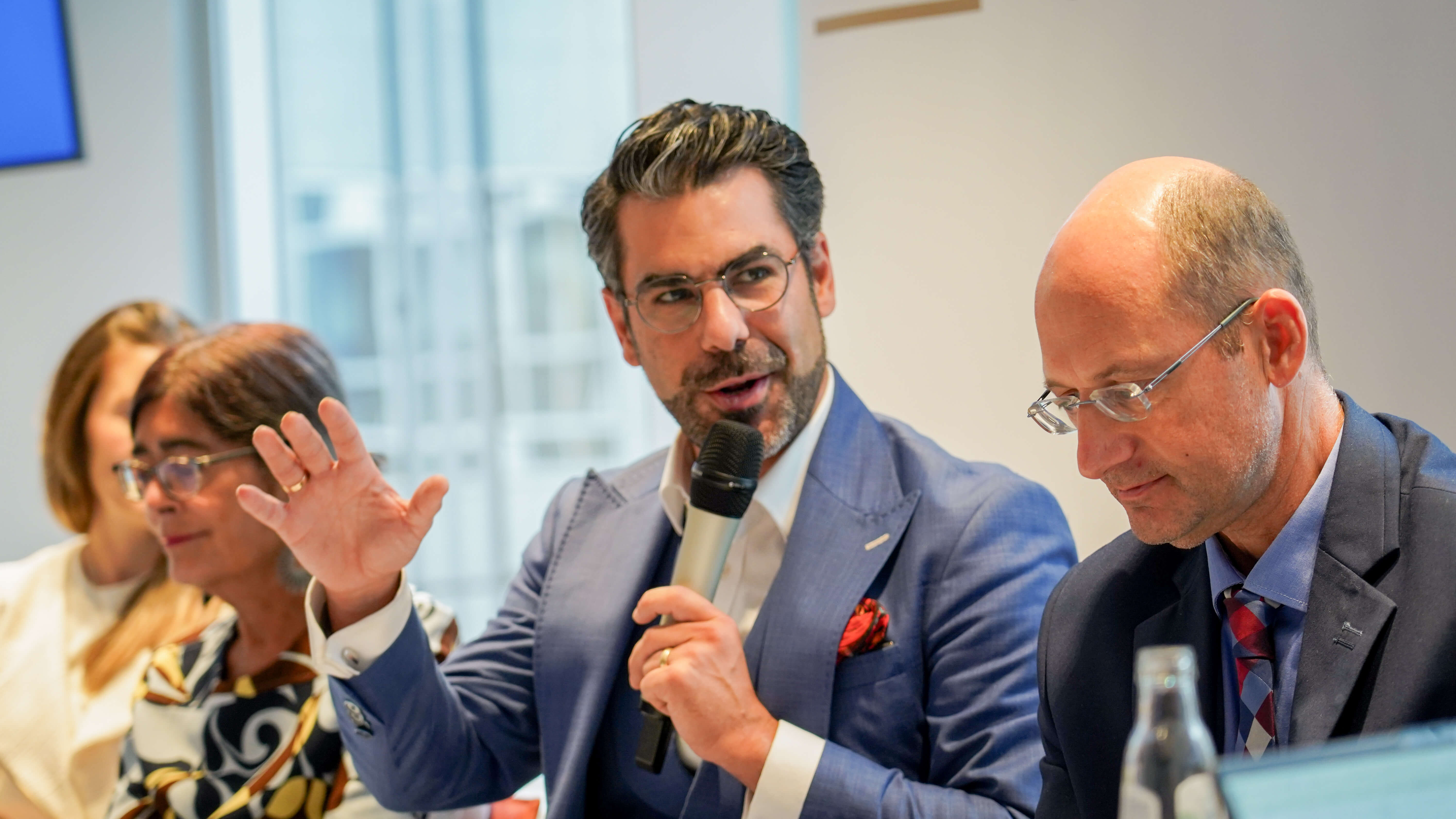 a man in a suit speaks at a conference