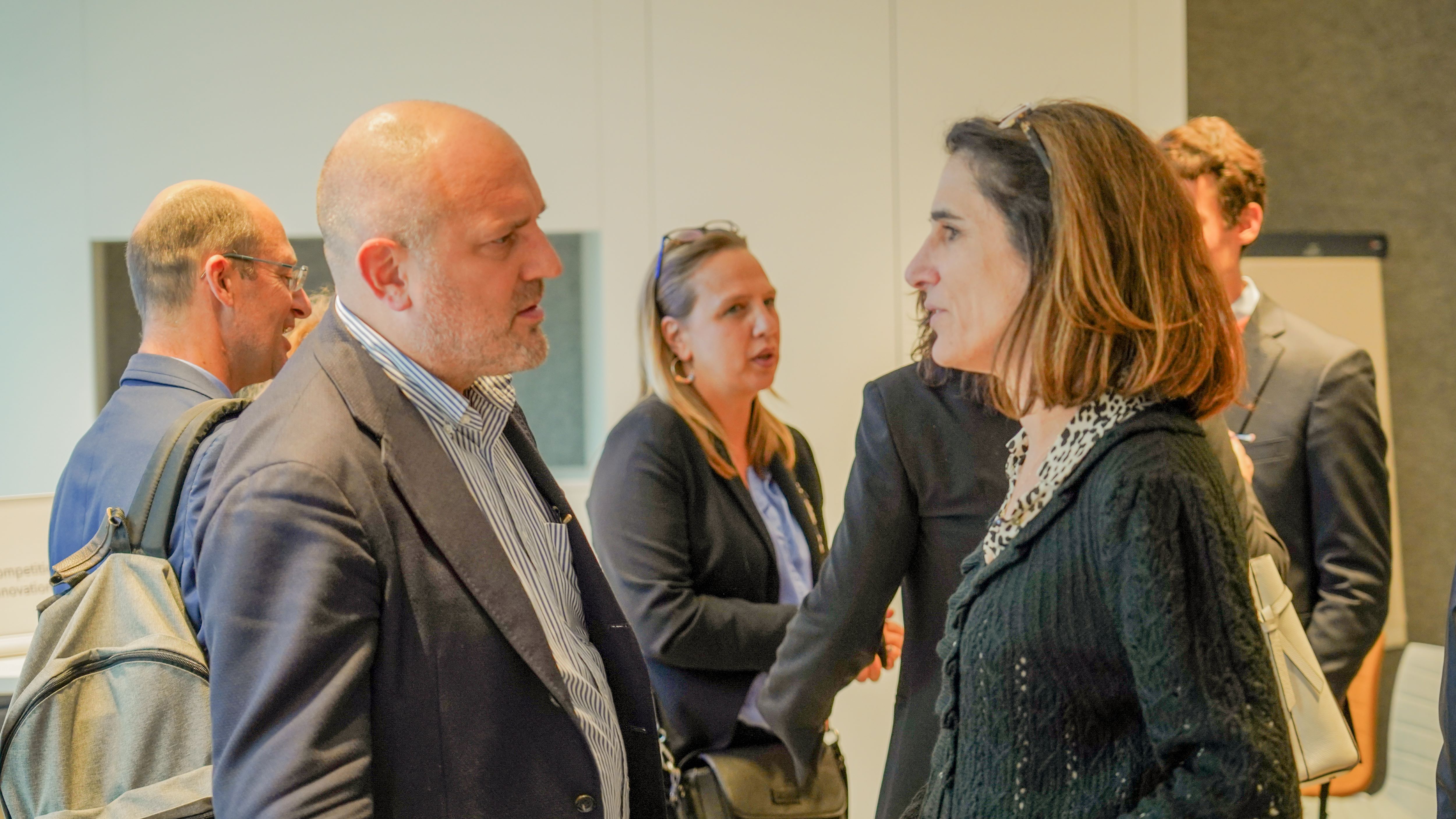 a man in a suit and a woman in business wear have a conversation at a conference