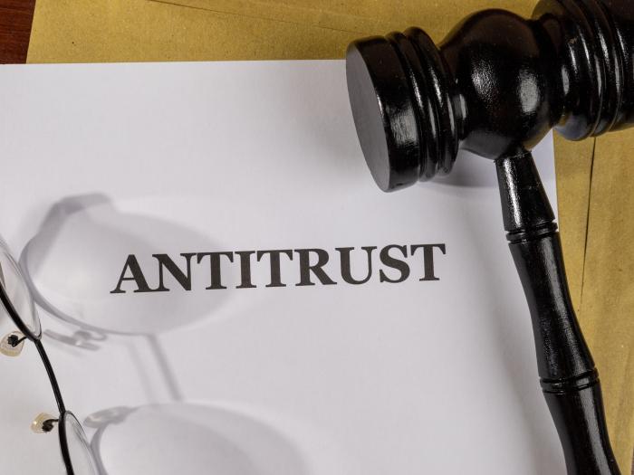 A gavel and a pair of glasses sit on a paper that says ANTITRUST
