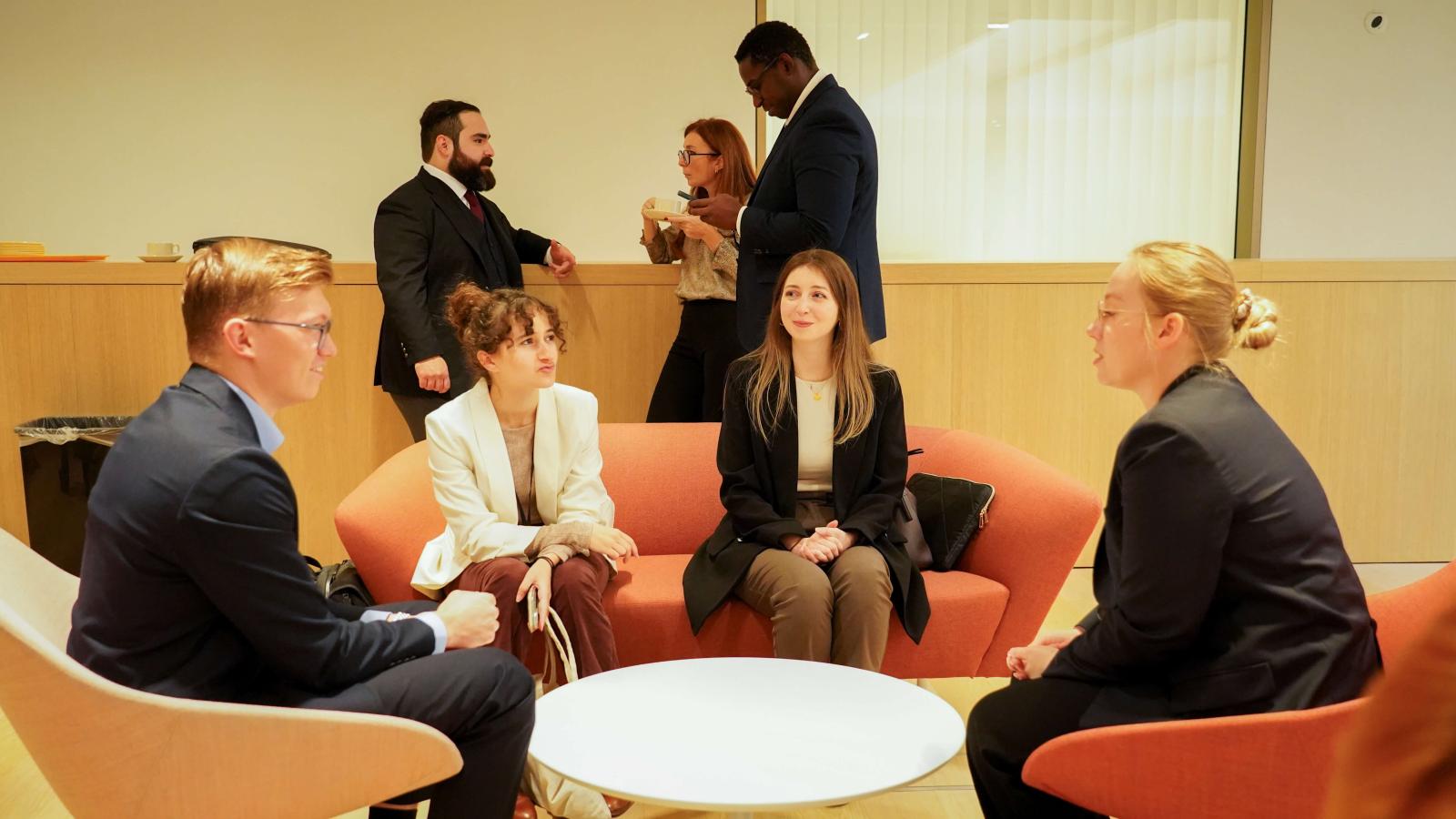 3 women and 1 man in business wear having a conversation at a conference