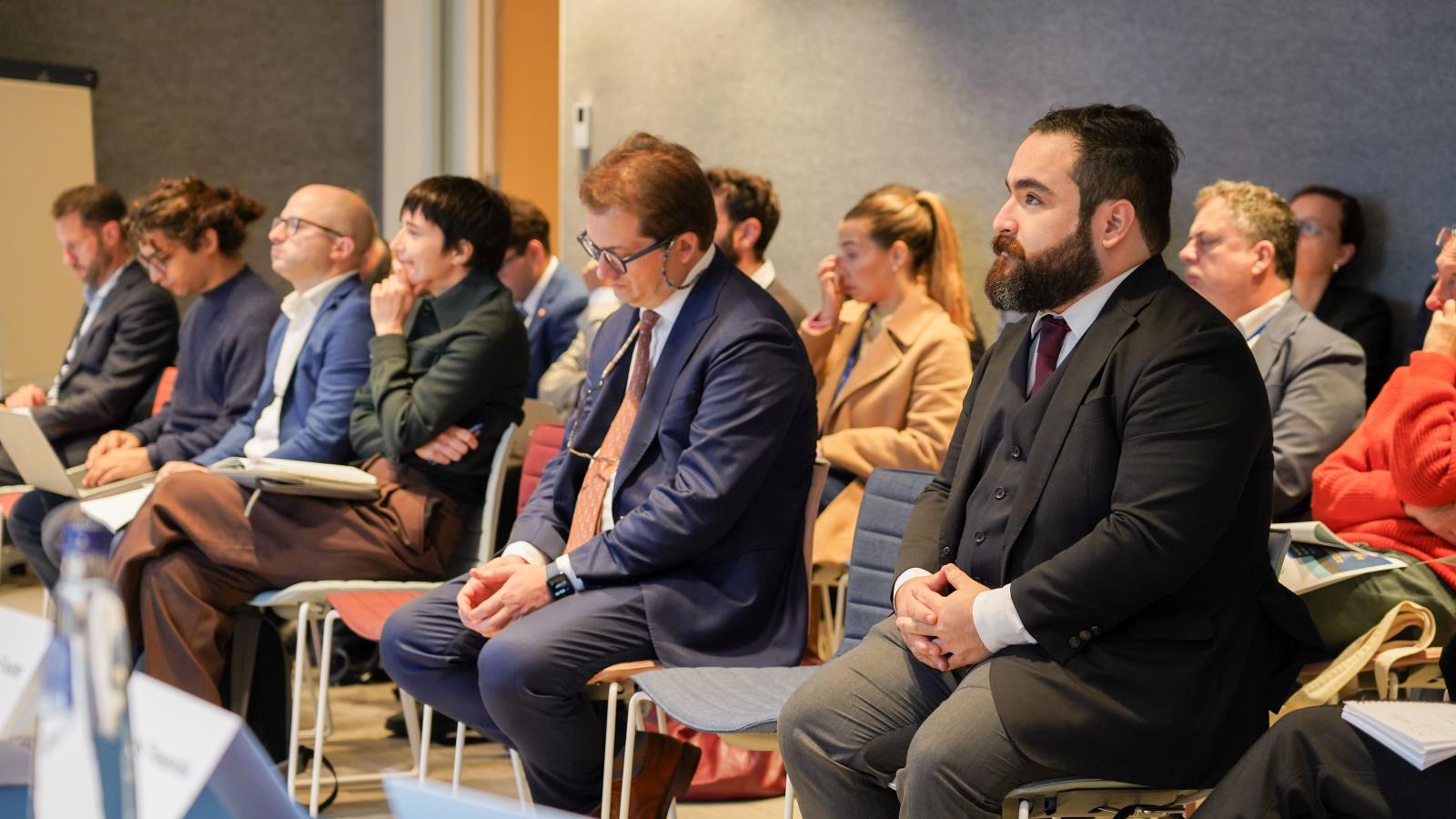 a crowd of people in business wear watches a conference presentation