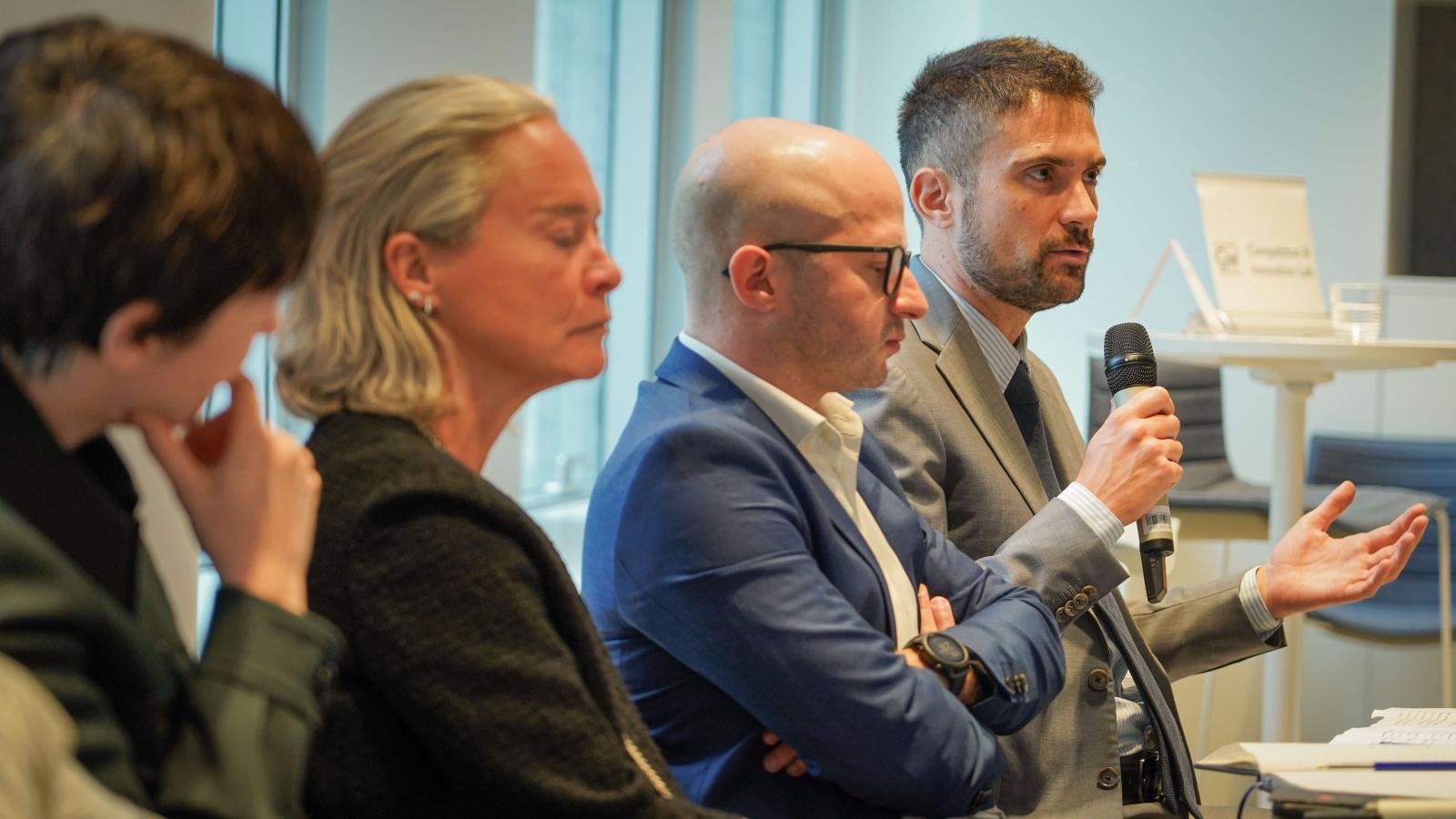 2 women and 2 men give a conference presentation on a panel