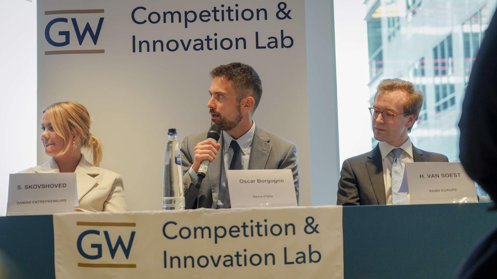 2 men and 1 woman in business wear on a panel at a conference