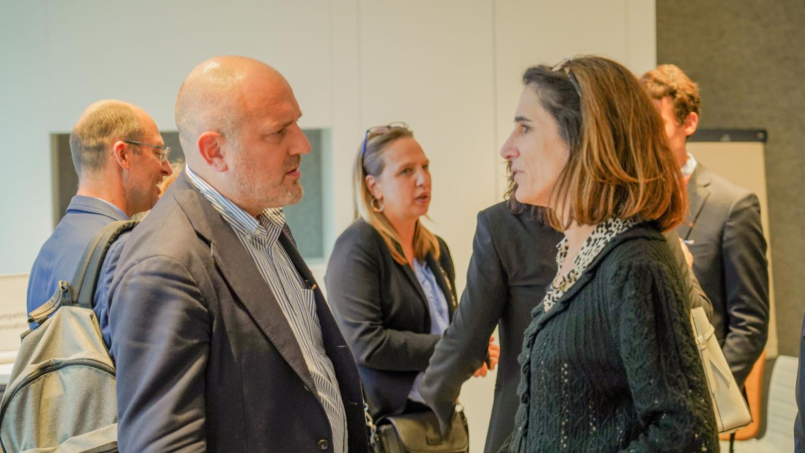 a man in a suit and a woman in business wear have a conversation at a conference